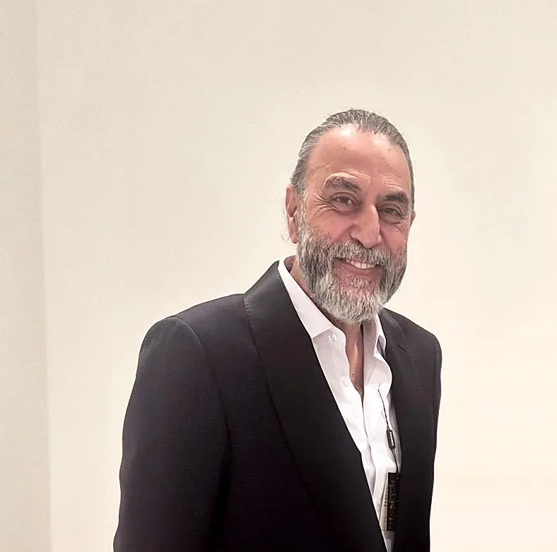 Mehran, smiling, in a dark jacket and an open white shirt