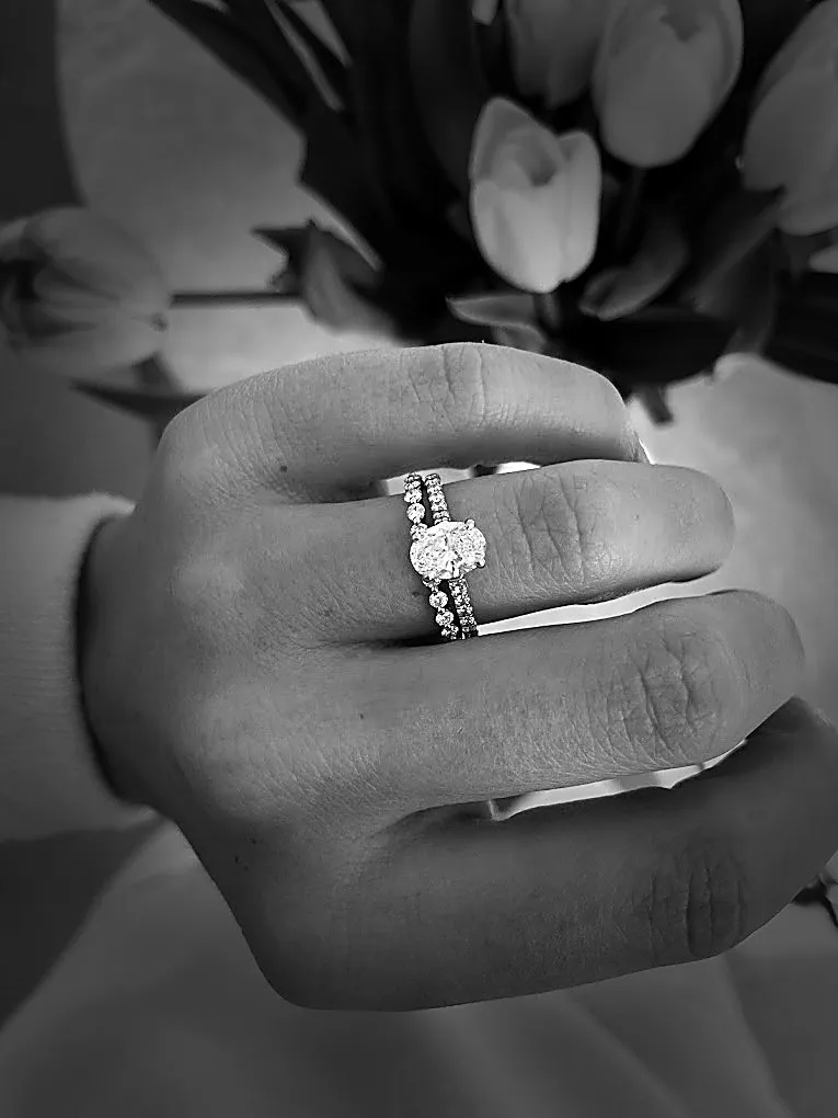 An engagement ring and its band, worn, with tulips behind